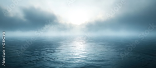 A calm ocean with a thick layer of fog in the distance, and a faint glimmer of sunlight breaking through.