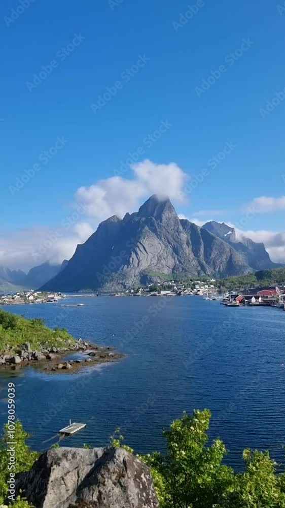 Discover the tranquility of Norwegian nature as clear waters embrace picturesque mountains. A sunny day enhances the charm of this scenic landscape, Reine, Lofoten, Norway Discover the tranquility of Norwegian nature as clear waters embrace picturesque mountains. A sunny day enhances the charm of this scenic landscape, Reine, Lofoten, Norway