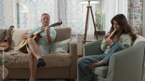 A middle-aged man and a 12-year-old girl enjoying a musical moment together, with him playing guitar and her playing a recorder flute in a cozy setting