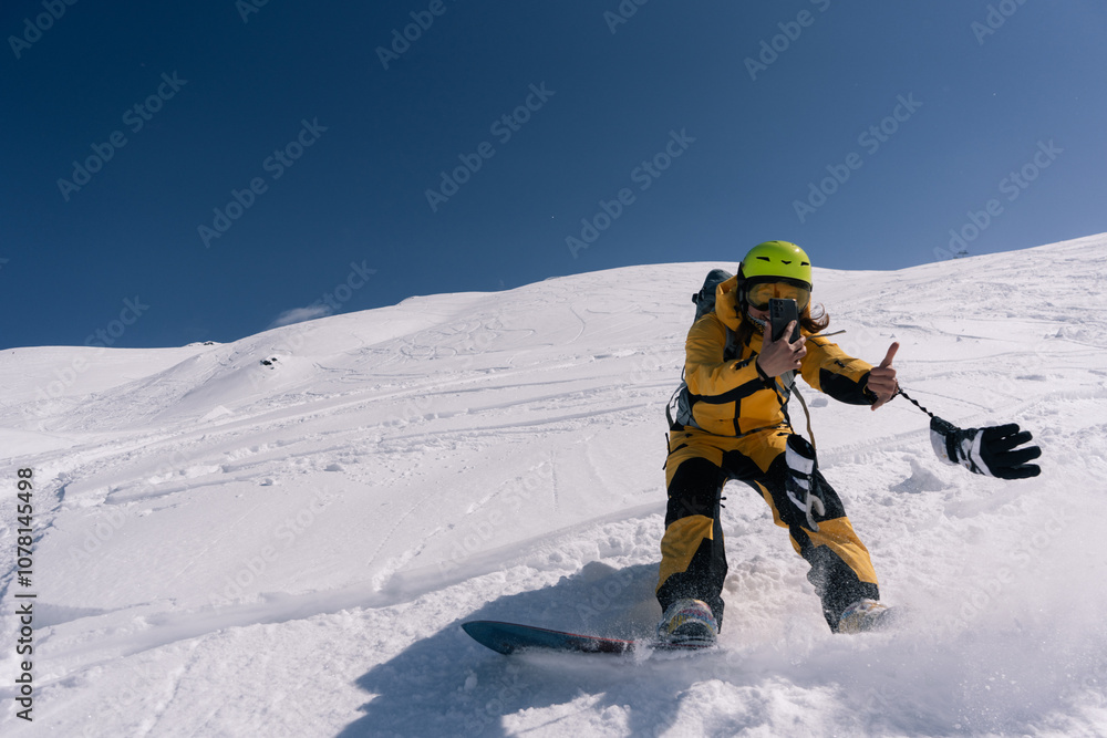 Woman snowboarder riding and taking photo on mobile phone on slope of powdery snow in high mountains. Freeride at ski resort Woman snowboarder riding and taking photo on mobile phone on slope of powdery snow in high mountains. Freeride at ski resort