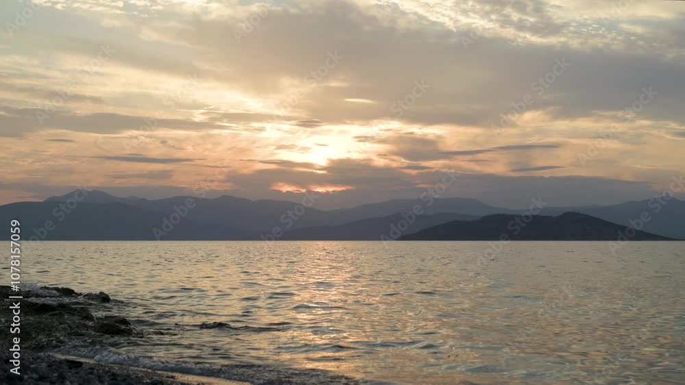 Calm ocean views with setting sun and small waves breaking on beach