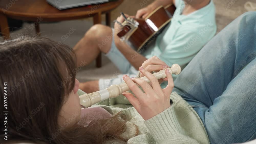 A middle-aged man and a 12-year-old girl enjoying a musical moment together, with him playing guitar and her playing a recorder flute in a cozy setting A middle-aged man and a 12-year-old girl enjoying a musical moment together, with him playing guitar and her playing a recorder flute in a cozy setting