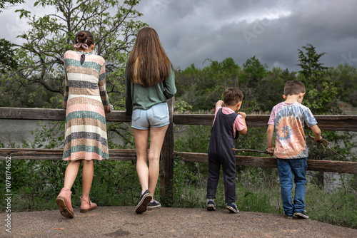 Four siblings stand by a wooden fence, overlooking a scenic lake