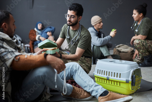 Foto Full length portrait of male volunteer offering food to group of Middle Eastern