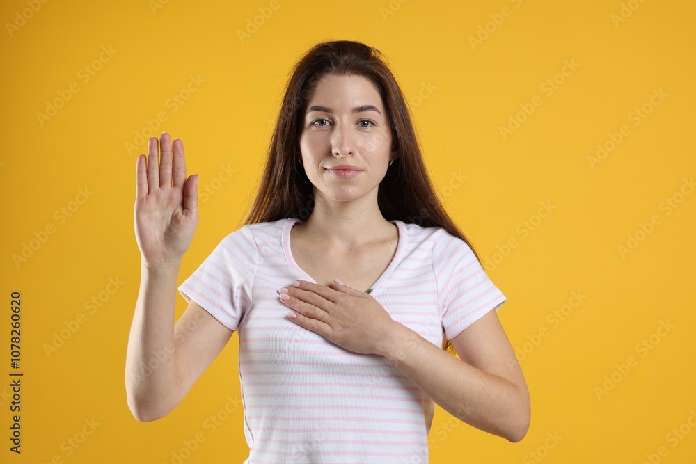 Woman making promise with raised hand on orange background. Oath gesture Woman making promise with raised hand on orange background. Oath gesture