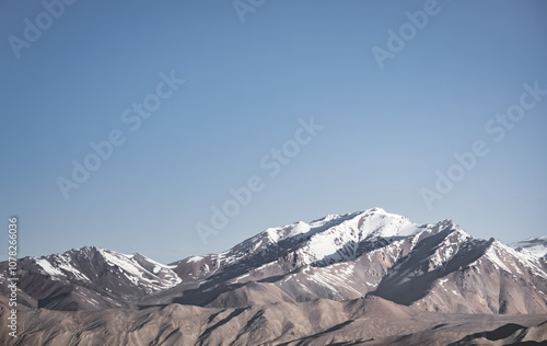 Mountain range of rocks covered with snow in highlands of Tien Shan in Pamir in Tajikistan, panoramic landscape of snowy mountain range and hills for background photo