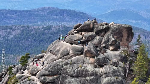 Hikers reaching the summit of a rocky formation in the mountains on a clear day in summer