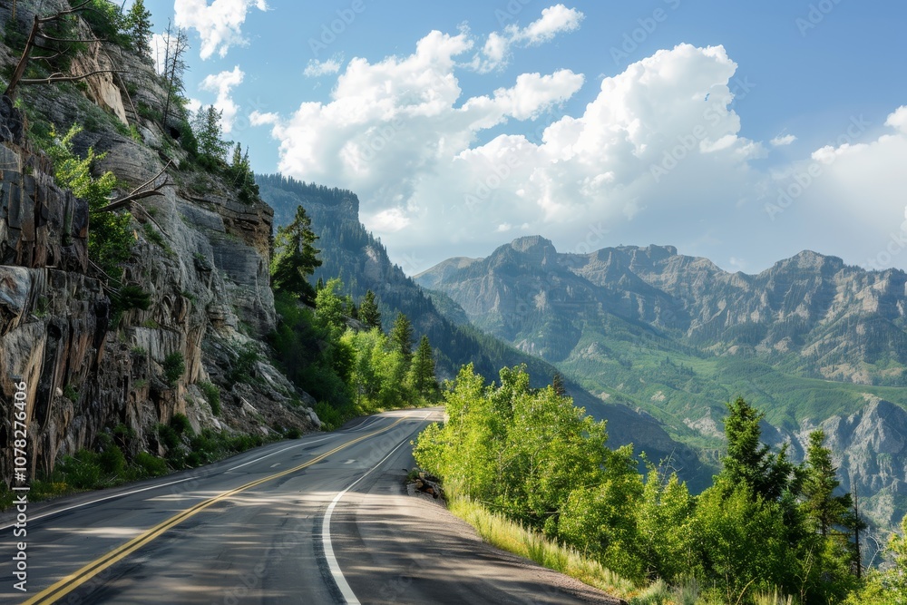 Scenic Mountain Road Winding Through Lush Greenery Under a Blue Sky With Puffy Clouds in a Picturesque Landscape