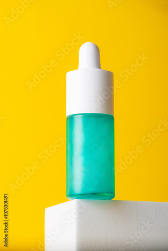 Blue glass cosmetic bottle, Skin care or sunscreen cosmetic with stylish props on yellow background.