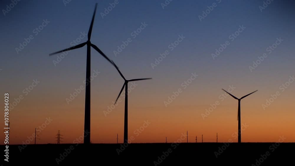 Silhouetted wind turbines rotate against a stunning gradient sunset sky, embodying renewable energy and sustainability. Ideal for eco-friendly, clean energy, and environmental themes. Silhouetted wind turbines rotate against a stunning gradient sunset sky, embodying renewable energy and sustainability. Ideal for eco-friendly, clean energy, and environmental themes.