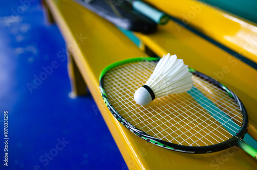 Badminton sport equipments  rackets and white feather shuttlecocks on floor in indoor badminton court  soft focus  endurance sports concept.