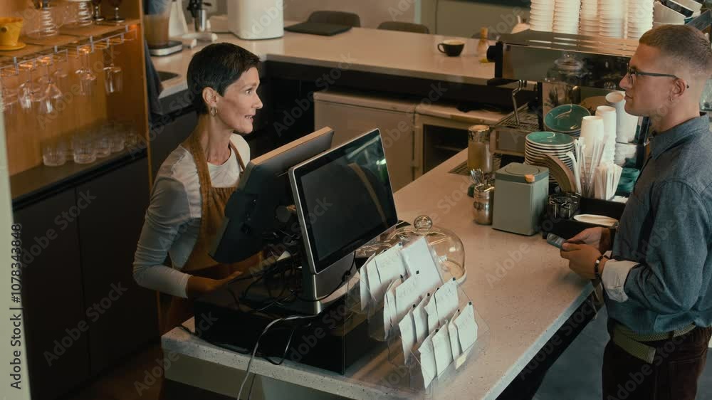 High angle view of young man making order in modern cafe and paying for it with bank card High angle view of young man making order in modern cafe and paying for it with bank card