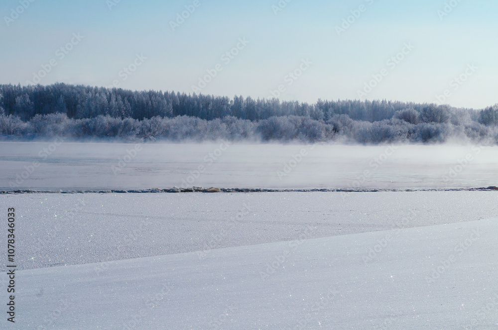Winter background - winter forest trees along the bank of the river and frozen river with fog in cold January day, winter background Winter background - winter forest trees along the bank of the river and frozen river with fog in cold January day, winter background