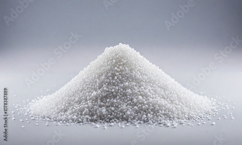 A pile of white granulated sugar sits on a gray surface