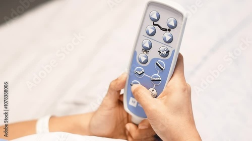 patient presses the up and down button on the remote control to raise and lower the head of the bed in the clinic to find a comfortable resting position, recovery and care concept,