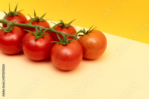 Red cherry tomatoes with green branch on yellow background	 photo