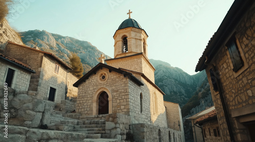 Stone church with bell tower and cross situated in a mountain village with traditional stone buildings and a clear sky backdrop photo