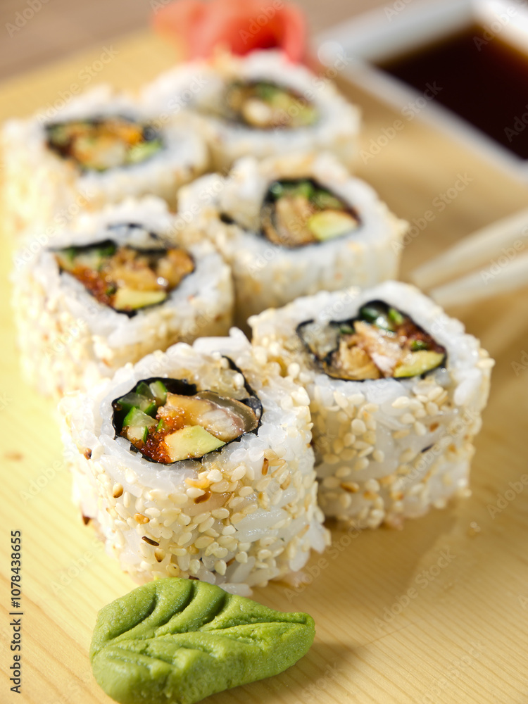 a sushi roll with eel fish, fly fish caviar and avocado on a wooden board decorated with wasabi in a leaf shape a sushi roll with eel fish, fly fish caviar and avocado on a wooden board decorated with wasabi in a leaf shape