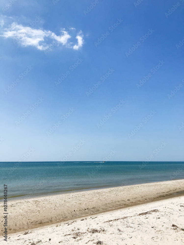 Serene beach with clear blue sky and calm ocean waves