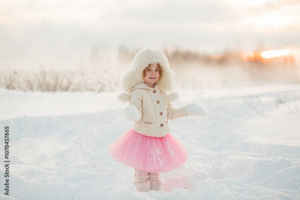 Winter lifestyle portrait of cheerful little girl in knitted sweater throwing snow in the air. Child is smiling and having fun in the snow park. Freedom and happiness concept. Winter lifestyle portrait of cheerful little girl in knitted sweater throwing snow in the air. Child is smiling and having fun in the snow park. Freedom and happiness concept.