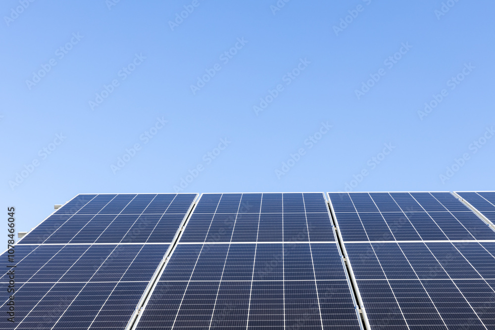 Aerial view of solar panel cells on clear blue sky background. Alternative energy concept. Modern house with solar panels stand-alone photovoltaic plant system on household metal sheet roof Aerial view of solar panel cells on clear blue sky background. Alternative energy concept. Modern house with solar panels stand-alone photovoltaic plant system on household metal sheet roof