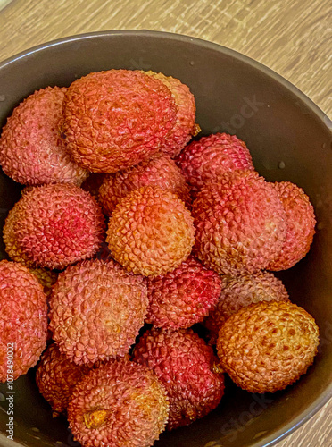  Fresh lychees in a bowl on a wooden table, close up
