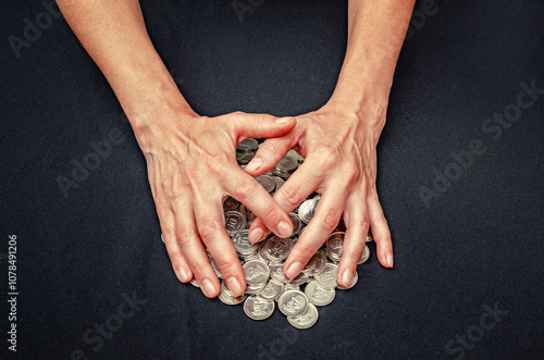 Hands cover heaps of silver coins. Close up concept of theft, misappropriation, fraud and greed. photo