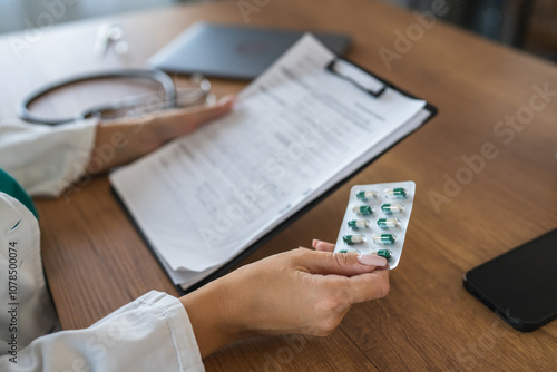 Doctor holds medicine blister pack with prescription on clipboard