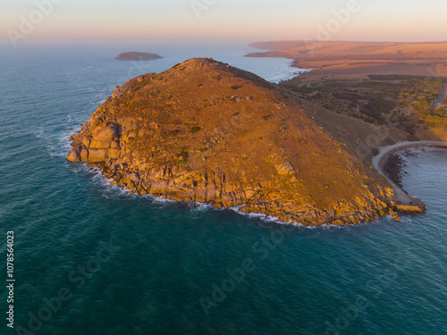 Aerial distant view of a rocky headland surrounded by a calm sea in early morning light photo