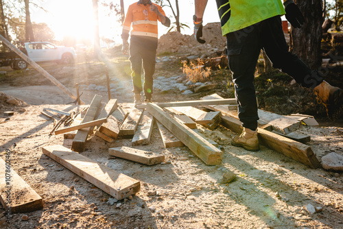 Builders sorting and checking wooden planks on the ground.