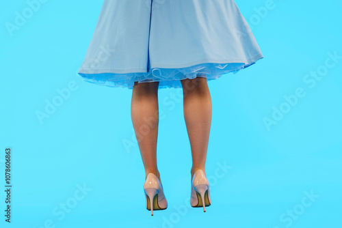 Elegant blue dress with high heels against a vibrant blue background highlights fashion and style in full view