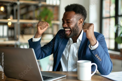 Excited man at laptop in office celebrates success and good news of approved financial loan for ecommerce startup and sales achievements