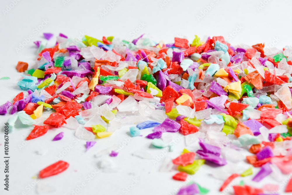 Various colored plastic waste shreds mixed on a white background, ready for the recycling process. Various colored plastic waste shreds mixed on a white background, ready for the recycling process.