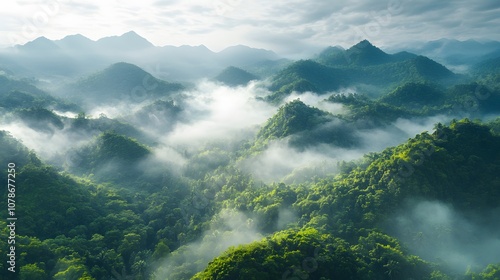 Ethereal mountain landscape with rolling hills shrouded in morning mist, featuring layered mountains and sunlight breaking through dense forest canopy. photo