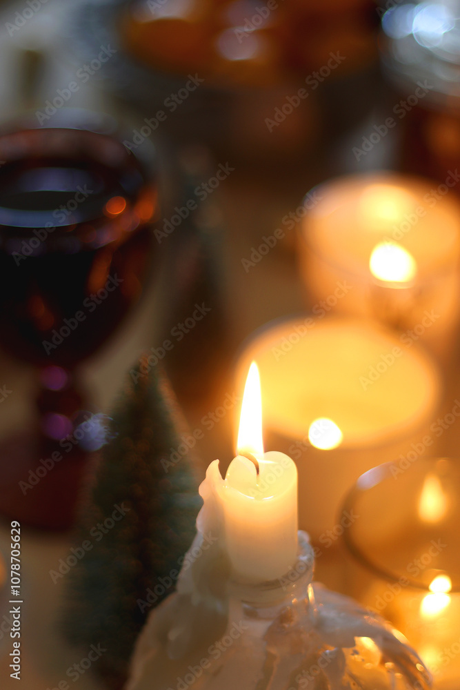 Various Christmas decorations, cookies, chocolate, nuts and tangerines, wine glasses and lit candles on the table. Holiday hygge at home. Selective focus. Various Christmas decorations, cookies, chocolate, nuts and tangerines, wine glasses and lit candles on the table. Holiday hygge at home. Selective focus.