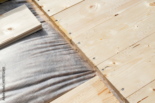 Close-up of wooden planks secured with screws over vapor barrier insulation for wooden house construction