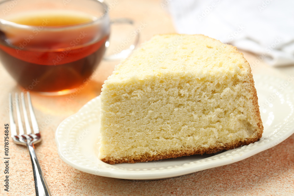 Piece of delicious sponge cake served on beige textured table, closeup Piece of delicious sponge cake served on beige textured table, closeup