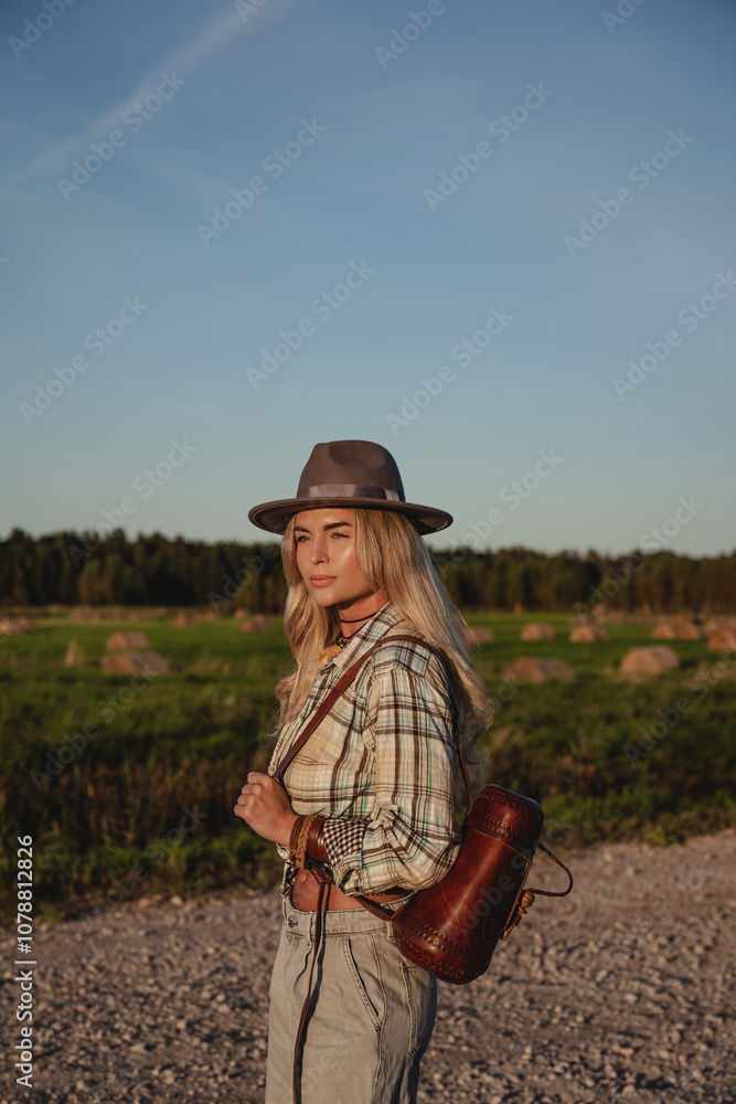 Fashionable woman walks along a gravel road in a rural setting Fashionable woman walks along a gravel road in a rural setting