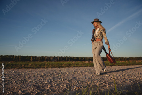 Fashionable woman walks along a gravel road in a rural setting