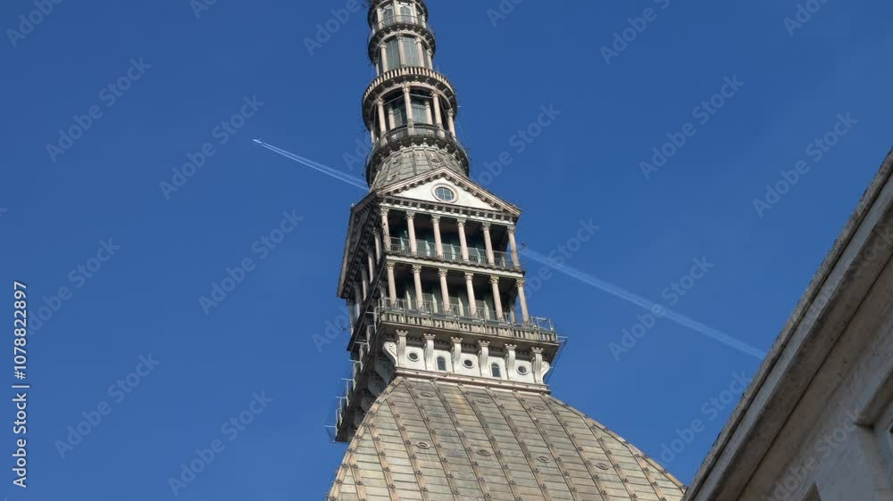 Italy, Turin, 11-10-2024. Low view, Mole Antonelliana detail with airplane in flight background in a sunny day. City of Turin. Super slow motion 4K Italy, Turin, 11-10-2024. Low view, Mole Antonelliana detail with airplane in flight background in a sunny day. City of Turin. Super slow motion 4K