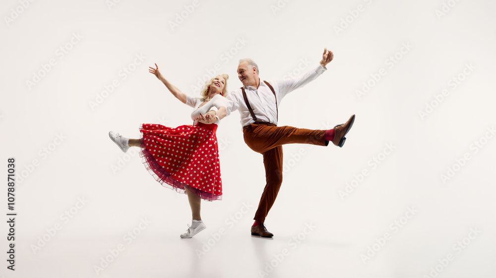 Φωτογραφία Senior couple, stylish man in suspenders and elegant woman in polka dot dress, dynamically dancing isolated on white background
