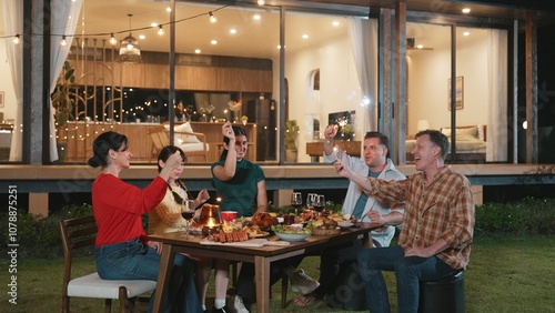 Happy family holding glowed sparkler in holiday celebration party at night. Lovely member enjoy playing spark toy together. Outdoor activity to cross generation gap strengthen family bond. Divergence.