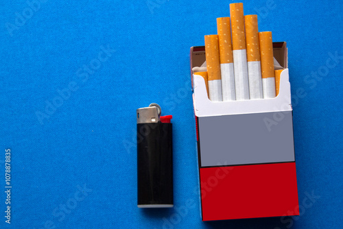 opened packet with  filtered cigarettes ,with a black lighter next to on blue background. selective focus 
