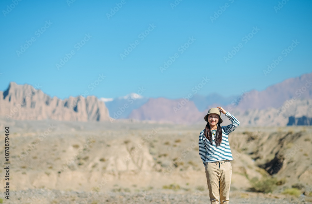 Fototapeta premium Asian female enjoying beautiful canyon landscape at Kuche Grand Canyon National Geopark, Xinjiang, China