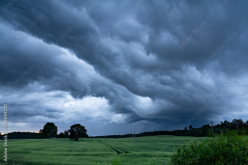 Obraz premium Dramatic storm clouds over green fields in Latvia