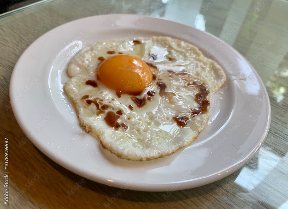 Breakfast Fried egg with soy sauce serve in white plate Served on the glass table Breakfast Fried egg with soy sauce serve in white plate Served on the glass table