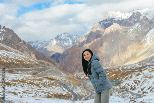 The autumn snowscape on the mountaintop of One beautiful Asian woman travels on Haxilegen Mountain along Duku Highway on the Pamir Plateau in Akto County, Xinjiang, China during September