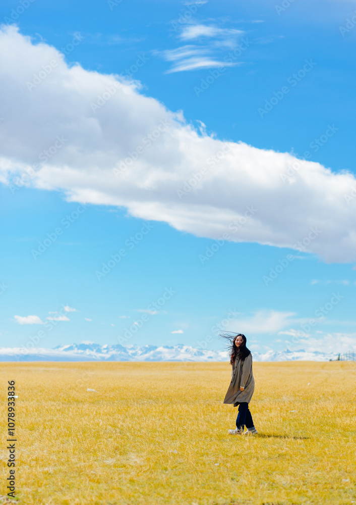 Asian woman enjoys beautiful autumn landscape at Bayanbulak Grassland along Duku Highway(Rd. G217) at Xinjiang, China Asian woman enjoys beautiful autumn landscape at Bayanbulak Grassland along Duku Highway(Rd. G217) at Xinjiang, China