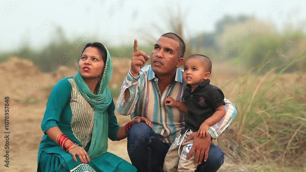 Slow motion mother and father standing outdoor in nature carrying child in lap and pointing up in the sky video portrait close up. Slow motion mother and father standing outdoor in nature carrying child in lap and pointing up in the sky video portrait close up.