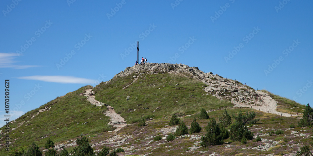 Fototapeta premium Touristes au sommet au pied de la croix du Mont Mézenc sommet de l'Ardèche et de la Haute-Loire